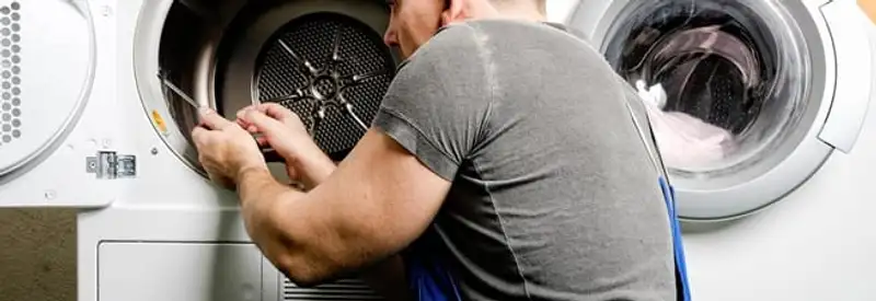 Dryer repair technician fixing a clothes dryer drum in Kansas City, MO