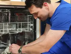 Dishwasher repair technician inspecting and servicing an open dishwasher in Kansas City, MO