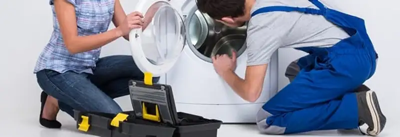 Washer repair technician inspecting a front-load washing machine with tools in Kansas City, MO