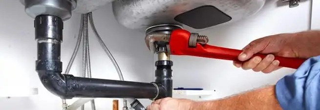 Garbage disposal repair technician tightening the sink drain and disposal connection in Kansas City, MO