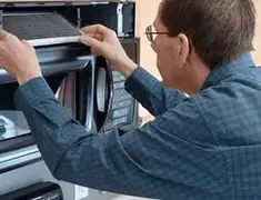 Appliance repair technician replacing a microwave vent filter in Kansas City, MO