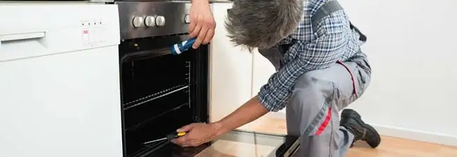Oven repair technician inspecting and servicing an electric oven in Kansas City, MO