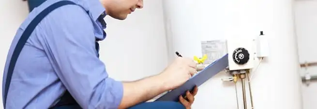 Water heater repair technician inspecting the unit and recording service notes in Kansas City, MO