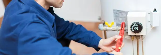 Water heater repair technician adjusting the temperature control and gas valve in Kansas City, MO